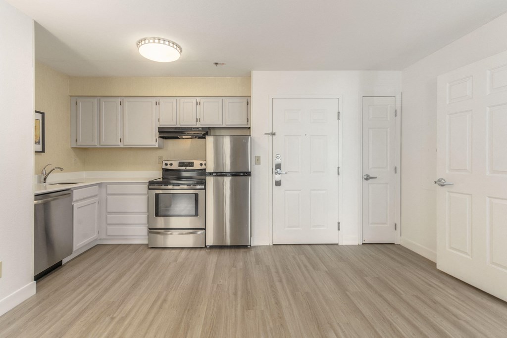 an empty kitchen with stainless steel appliances and white cabinets